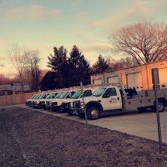 Tow trucks parked near a building during dusk.