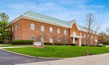 Two-story brick office building with green roof and well-manicured lawn.