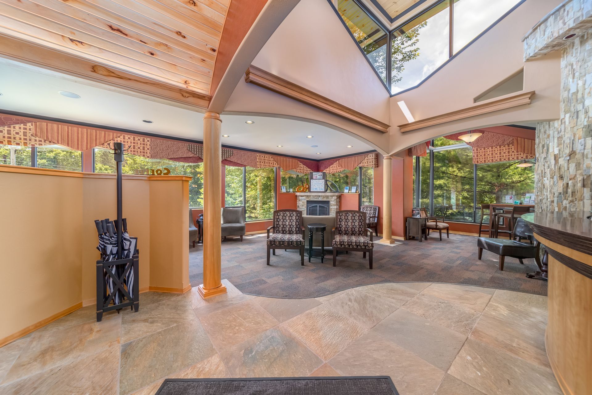Bright open patio with stone floor, wood ceiling, skylight, and tables near large windows.