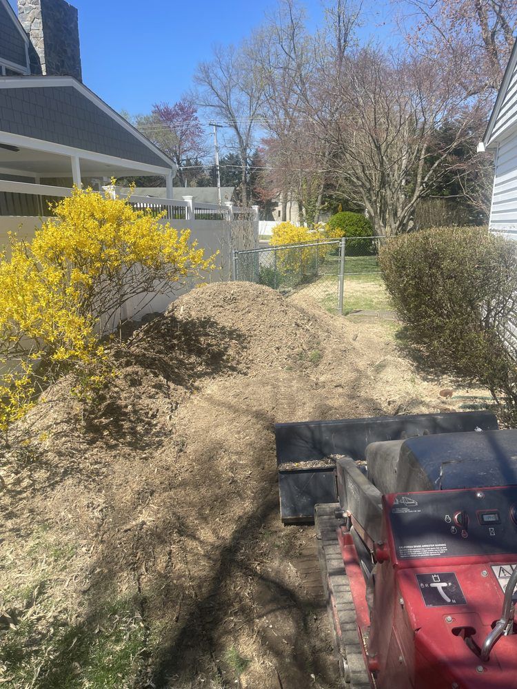 A red tractor is moving dirt in a yard next to a house.