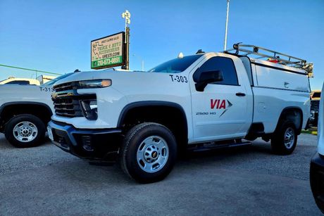 White VIA service truck parked outside with a commercial topper