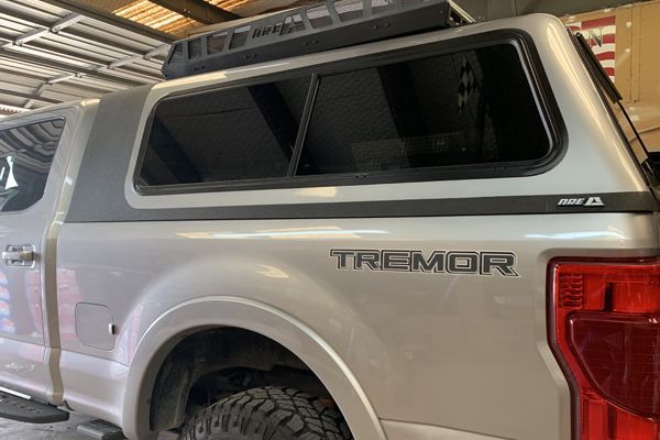 A silver camper with a canopy on top of it is parked in a garage.