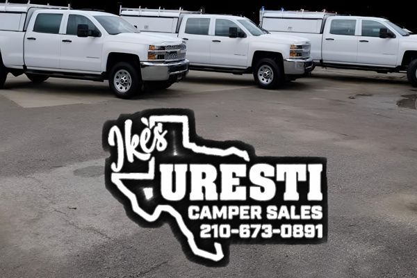 Three white trucks are parked in a parking lot