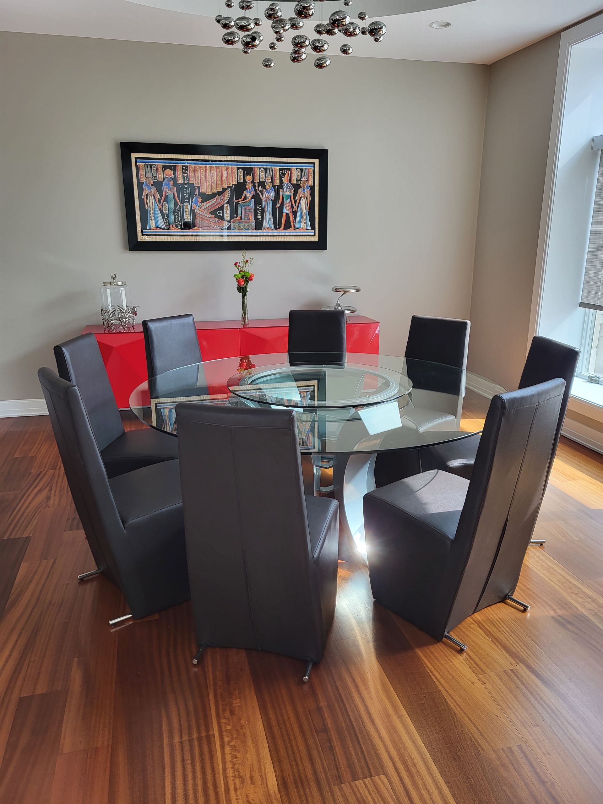 A dining room with a round glass table and black chairs