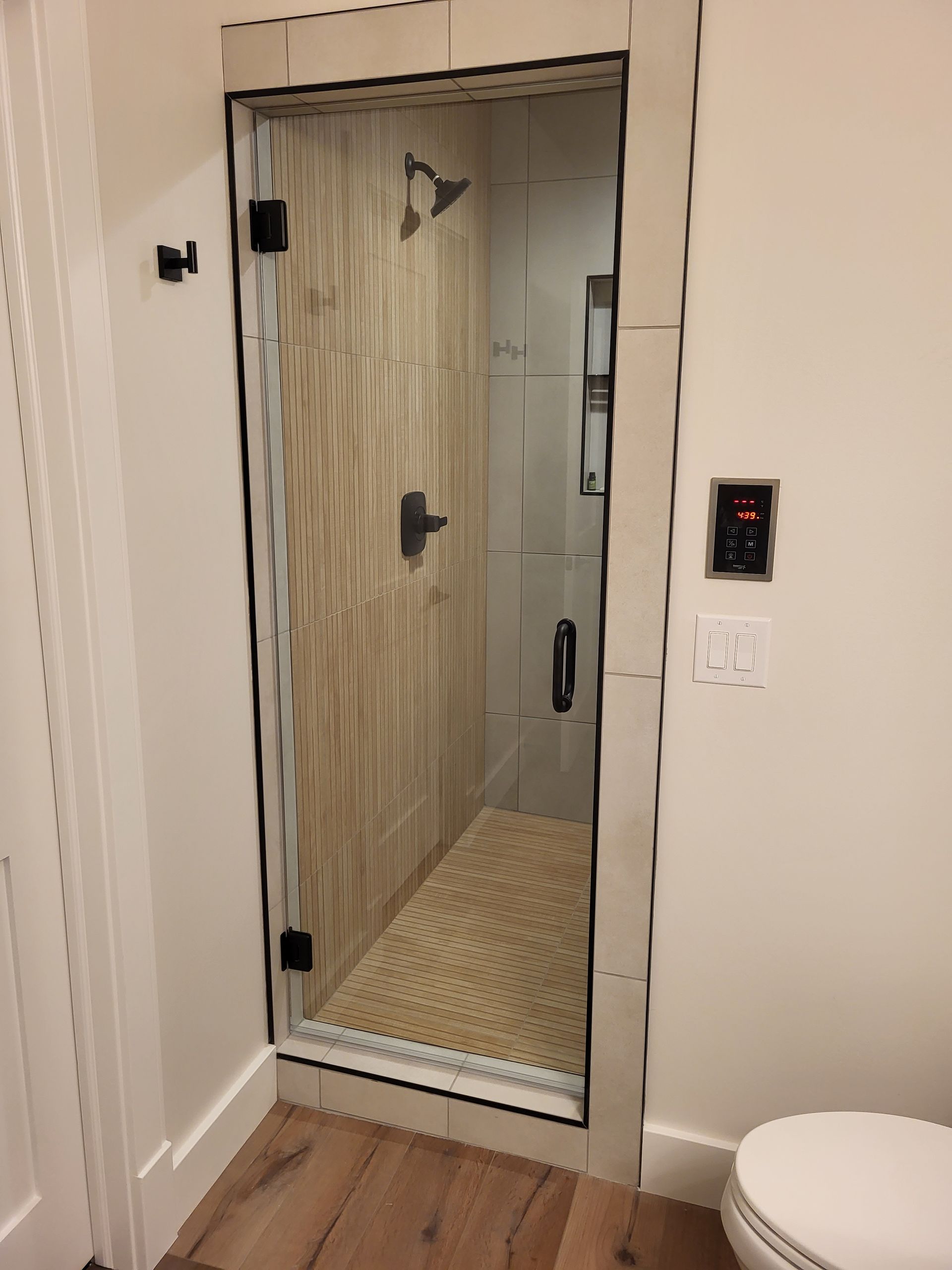 A bathroom with a glass shower door and a toilet