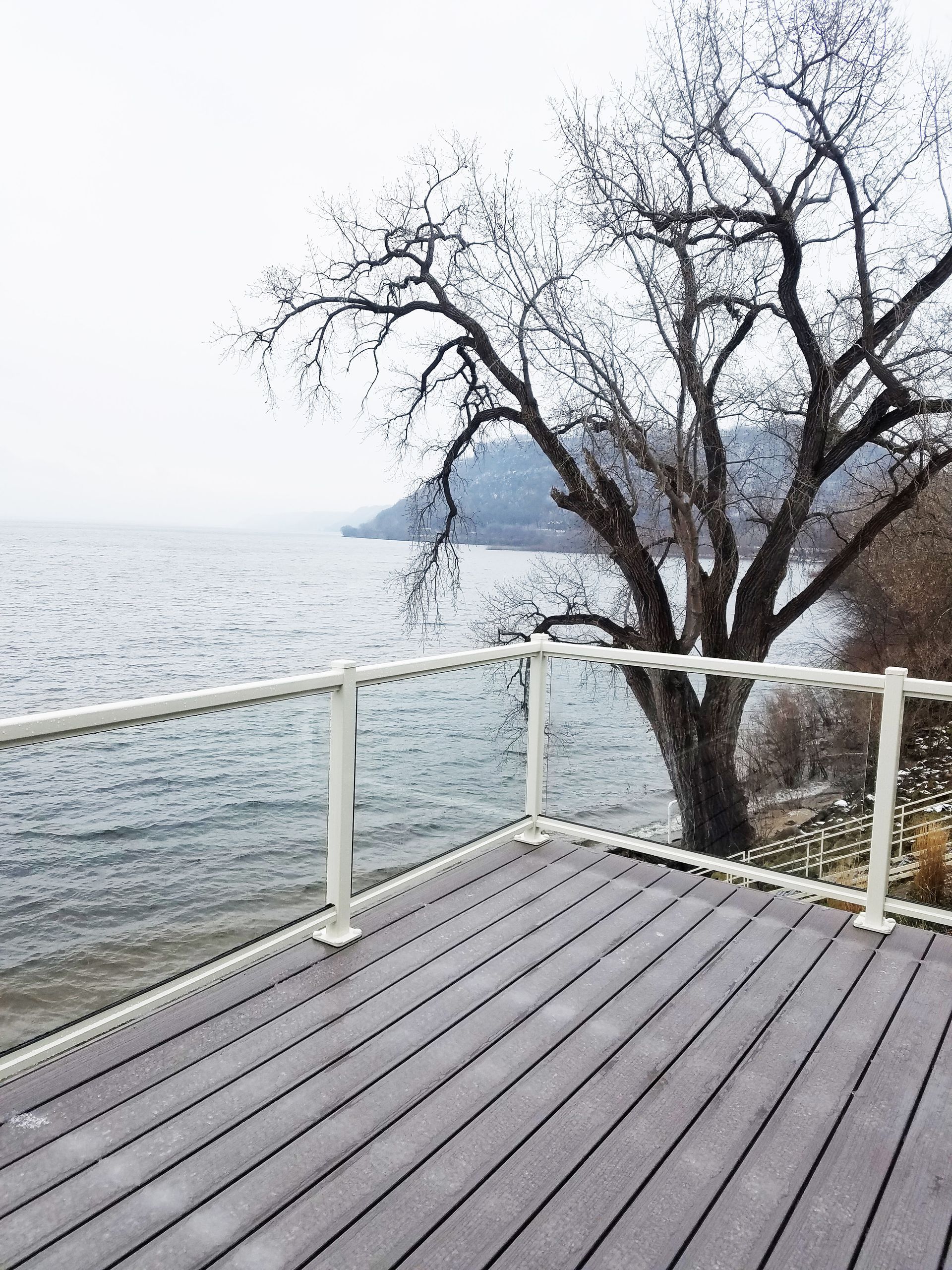 A deck overlooking a body of water with a tree in the background
