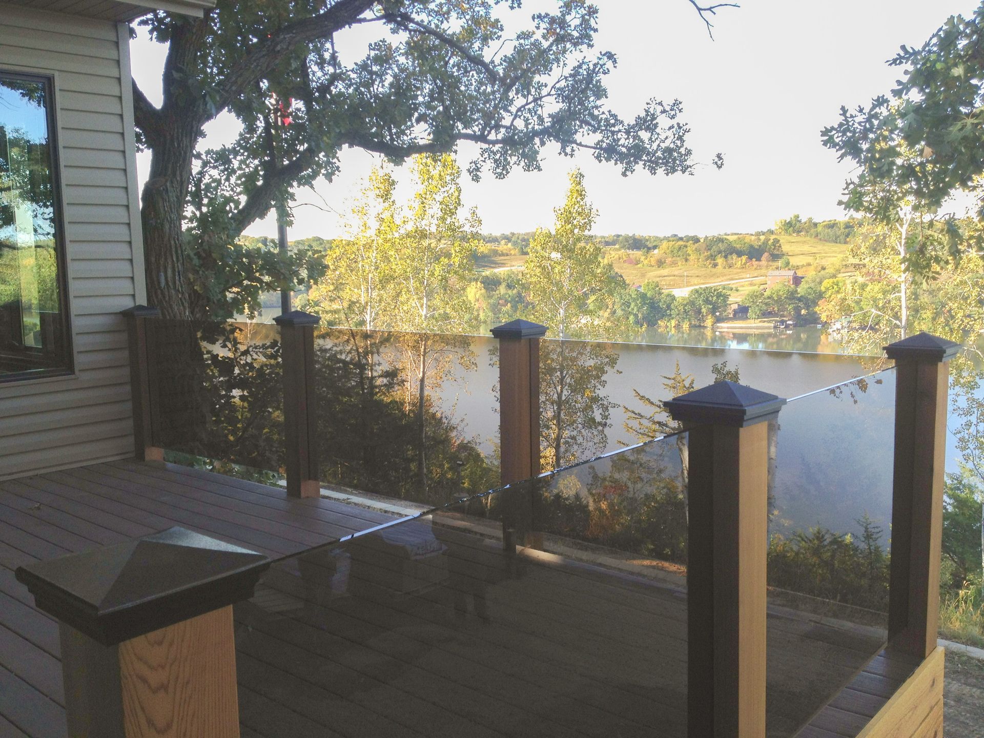 A deck with a glass railing overlooking a lake