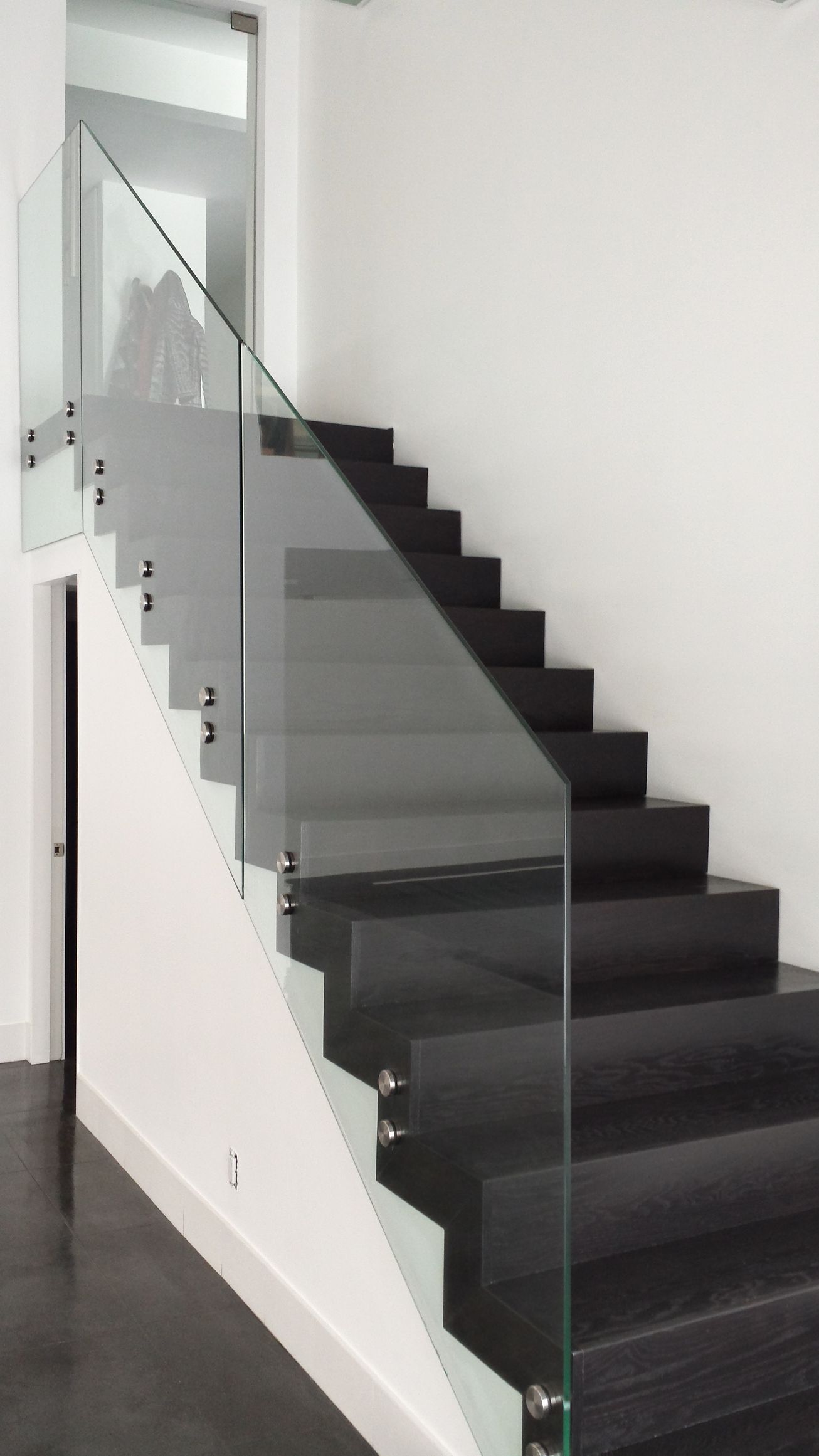 A black staircase with a glass railing in a room