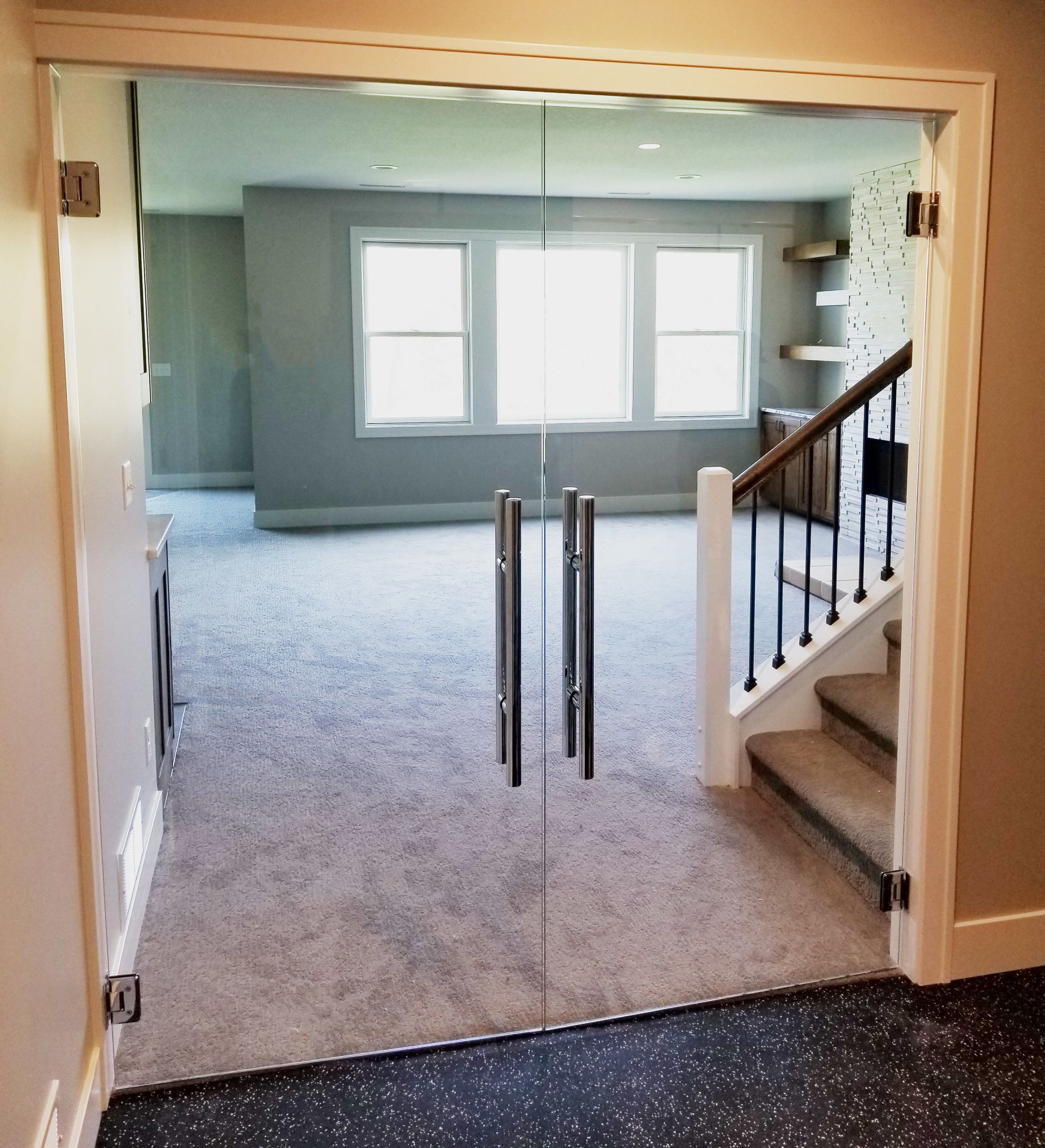 A glass door opens to a living room with stairs