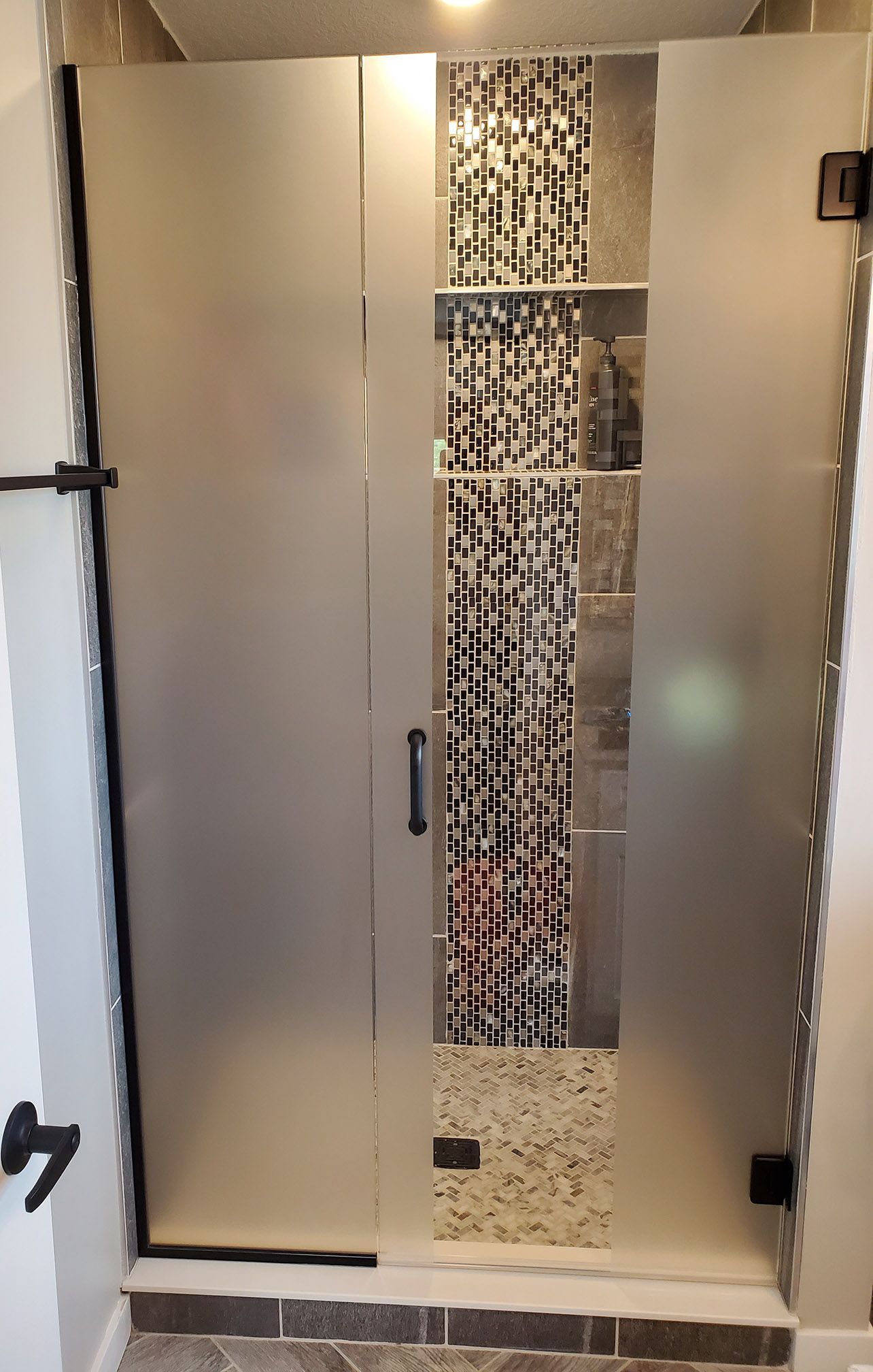 A bathroom with a glass shower door and a mirror