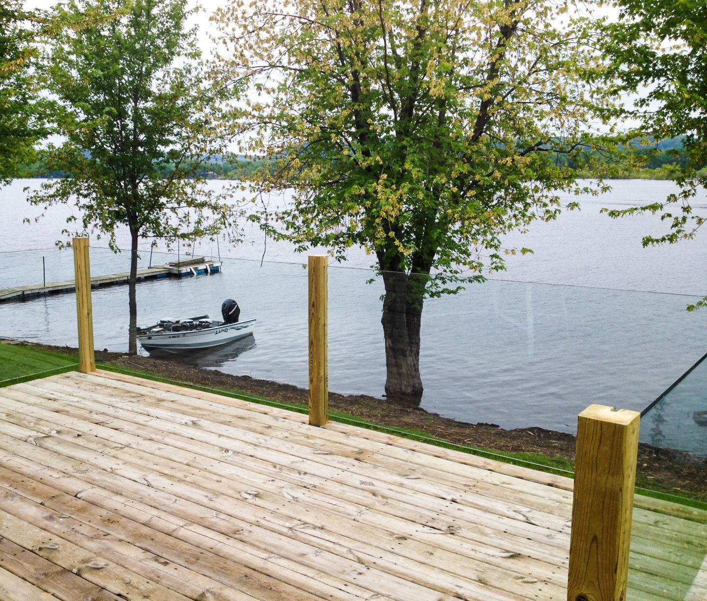 A wooden deck overlooking a lake with a boat in the water