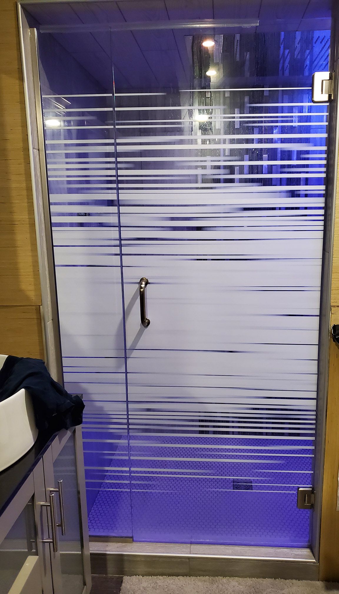 A glass door with a blue light behind it in a bathroom