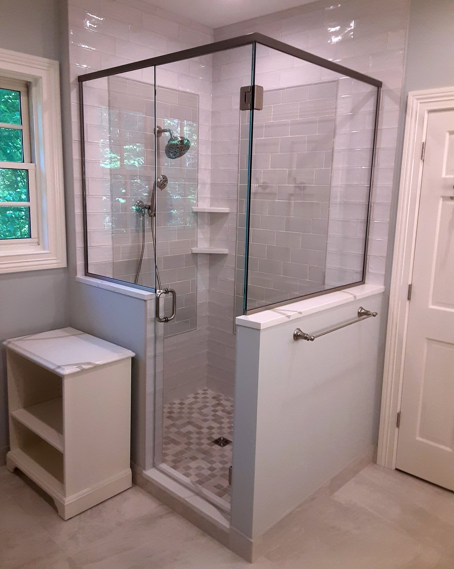 A bathroom with a walk in shower with a glass door