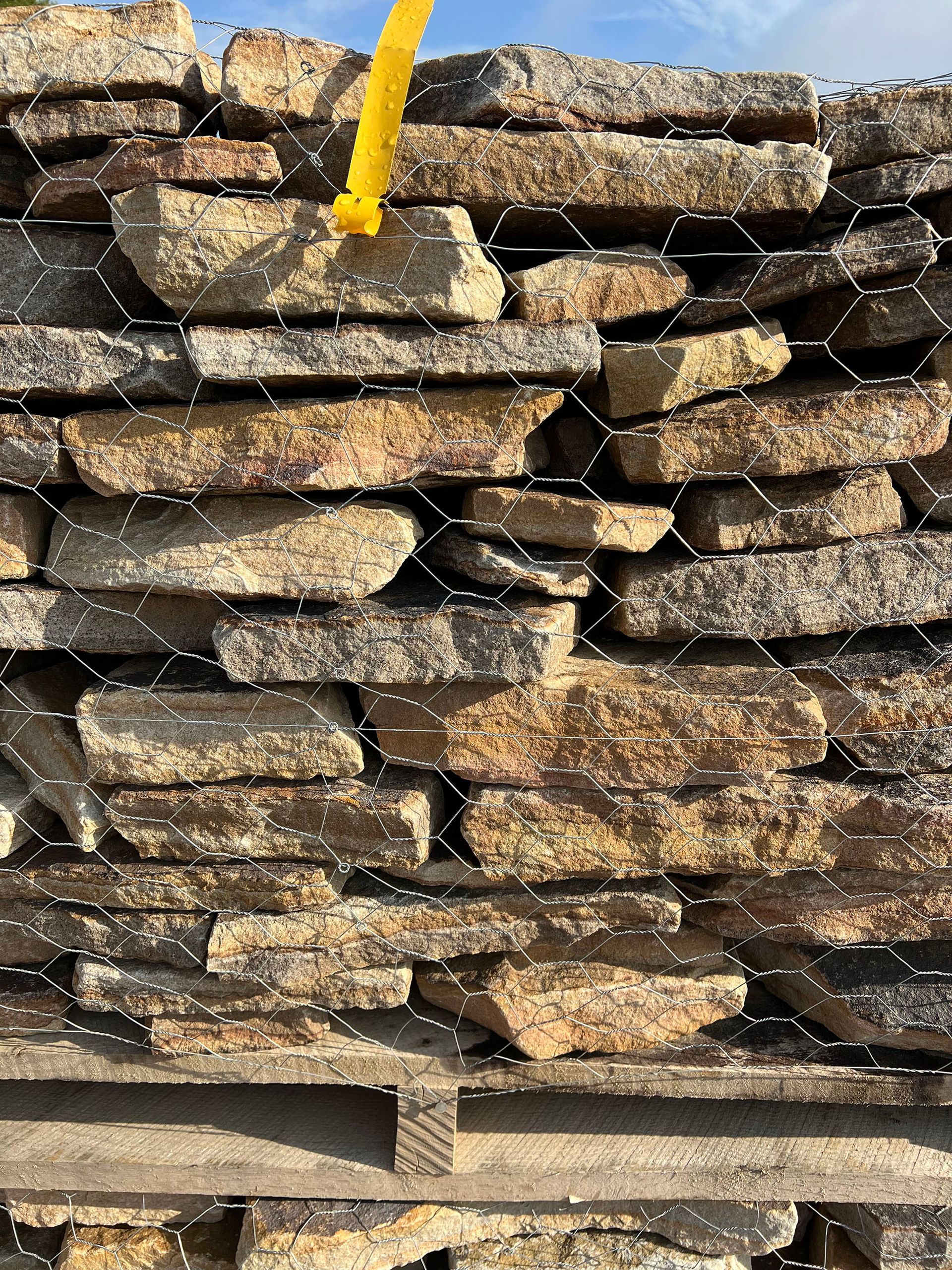A pile of rocks sitting on top of a wooden pallet behind a chain link fence.