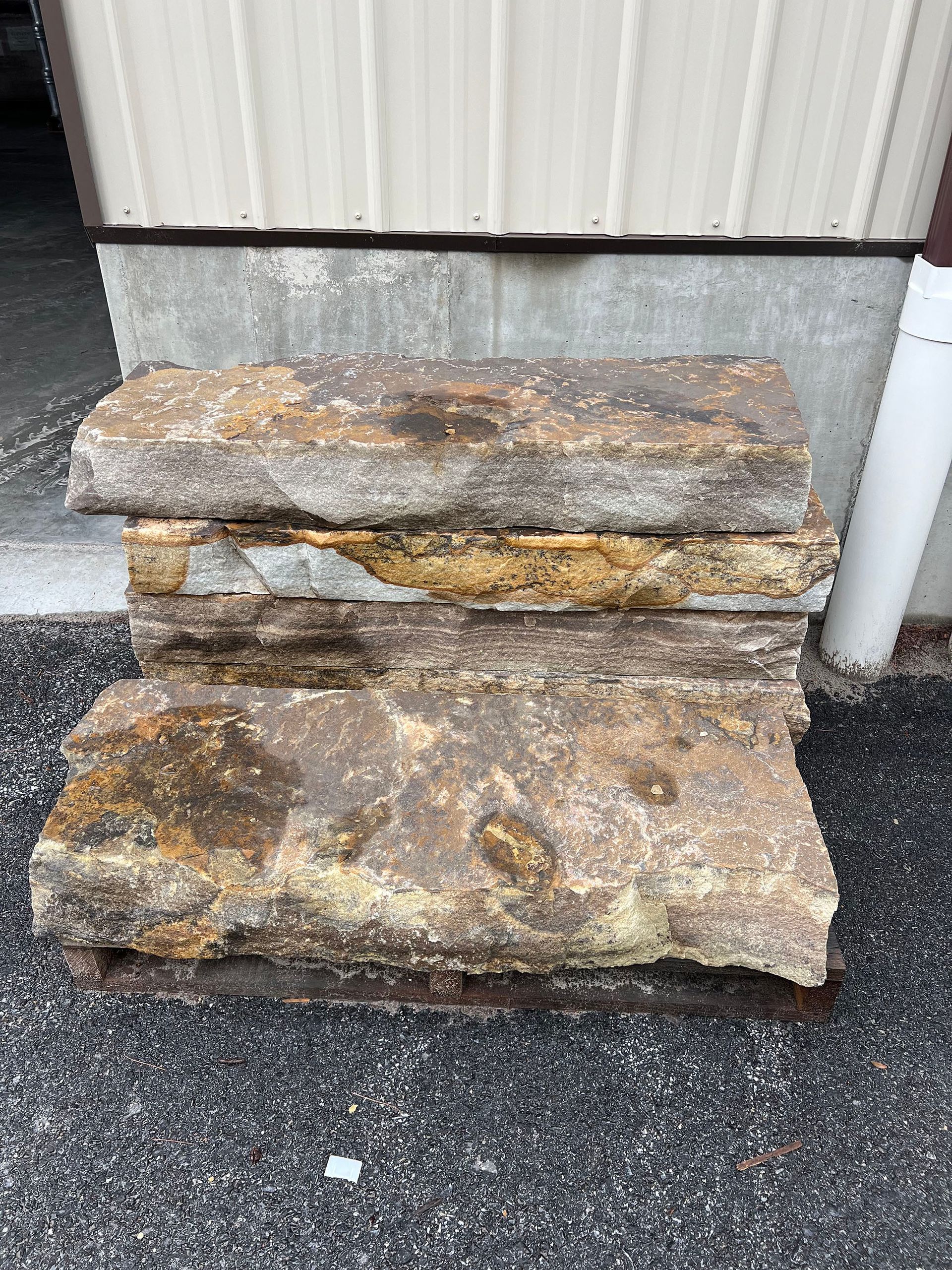 A pile of rocks sitting on top of a pallet in front of a building.