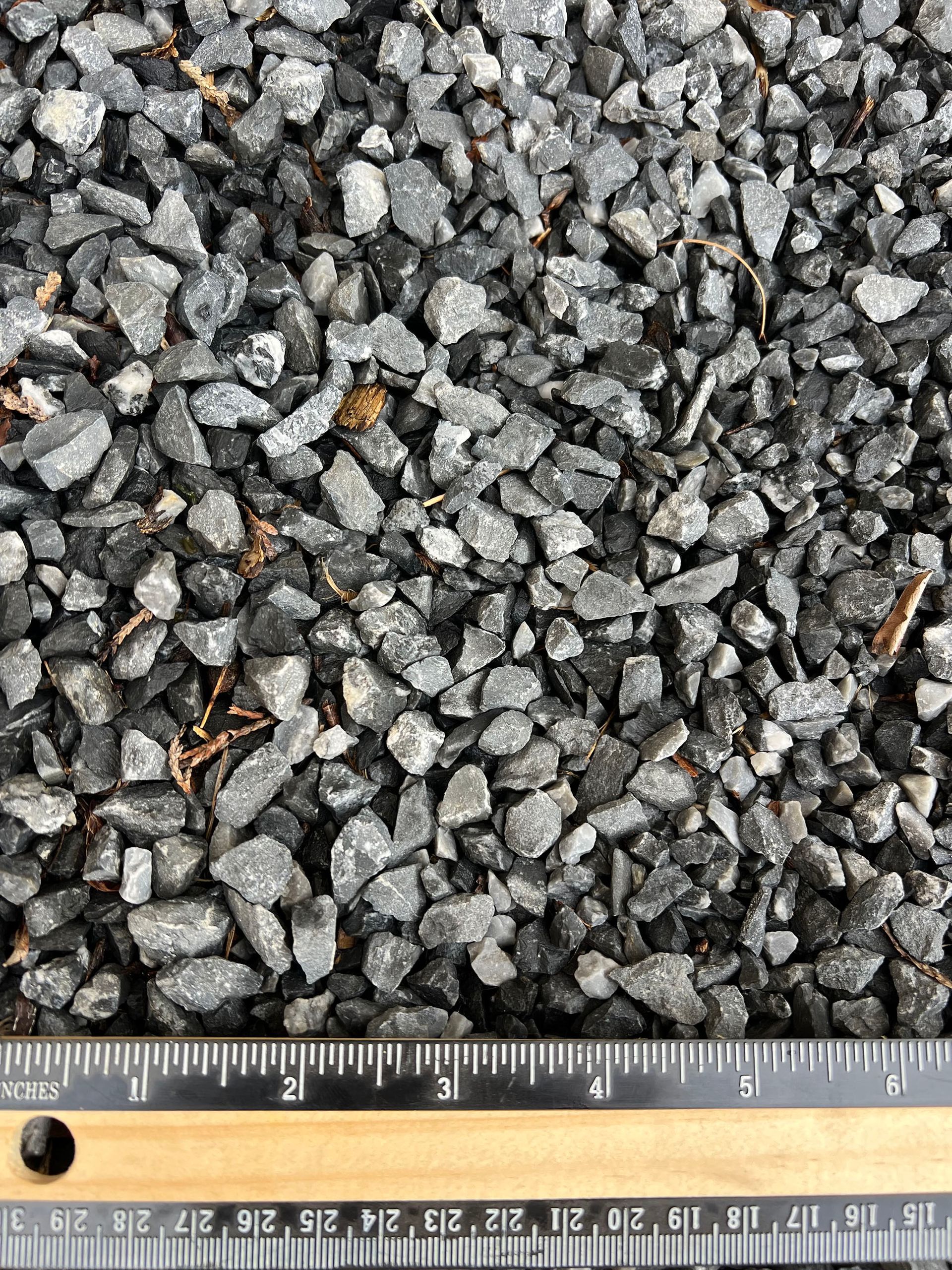 A pile of gravel is being measured with a ruler.