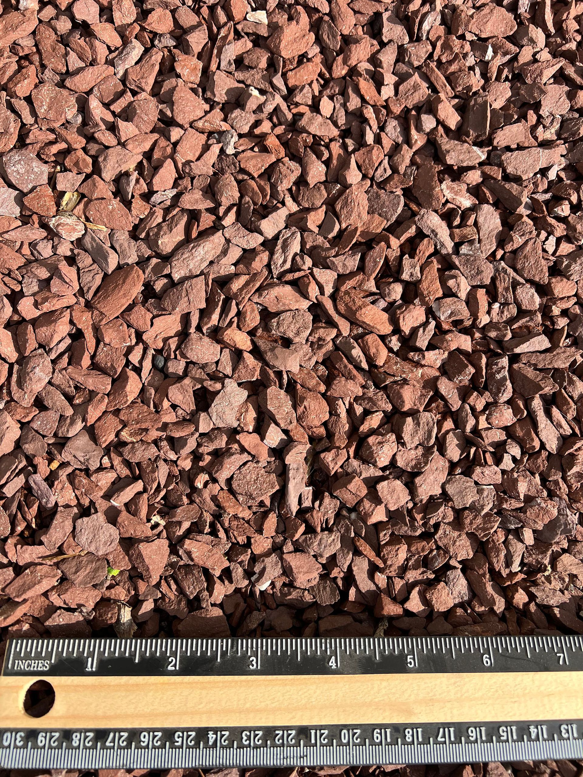 A ruler is sitting next to a pile of brown gravel.