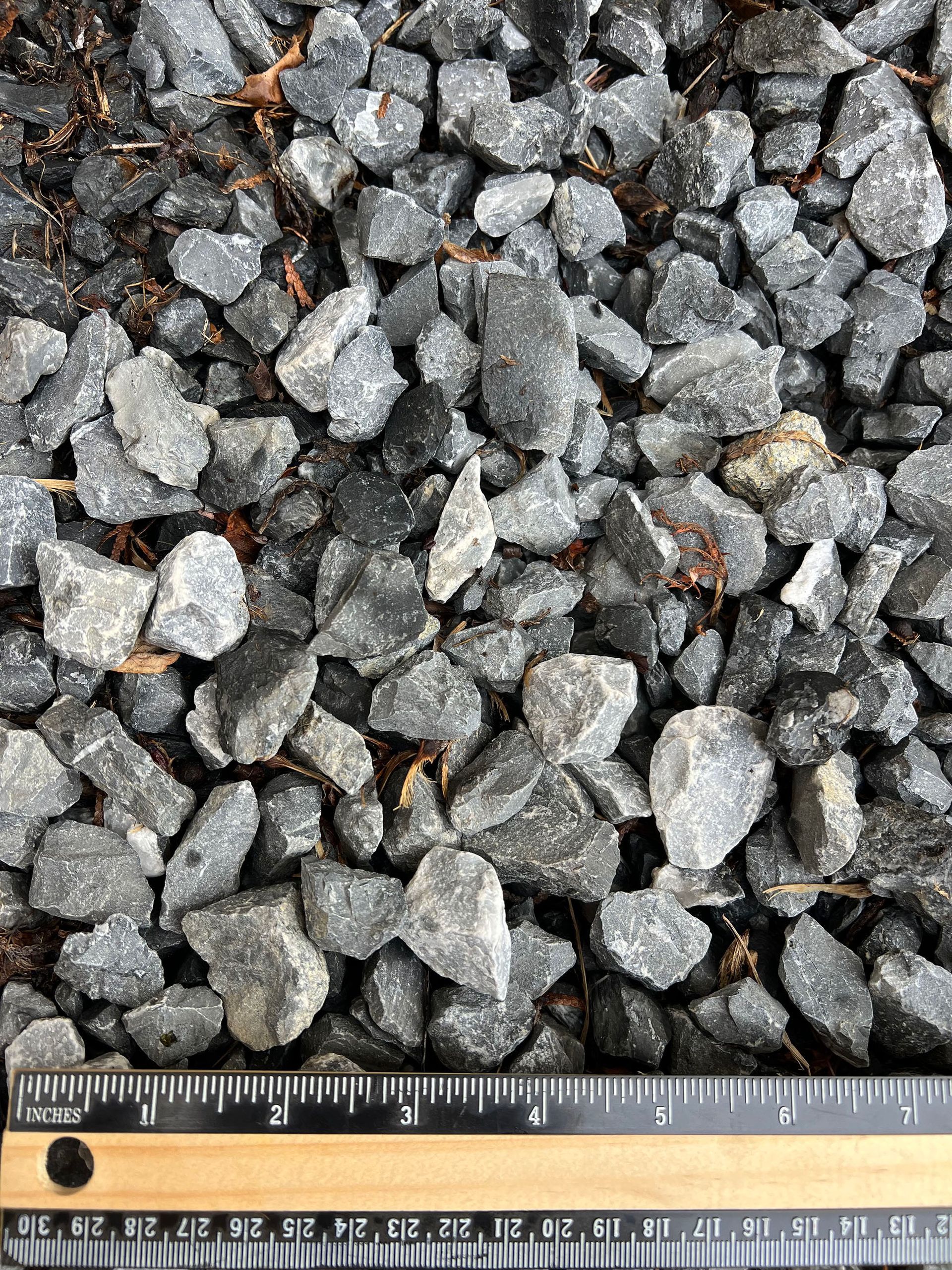 A pile of rocks is being measured with a ruler.