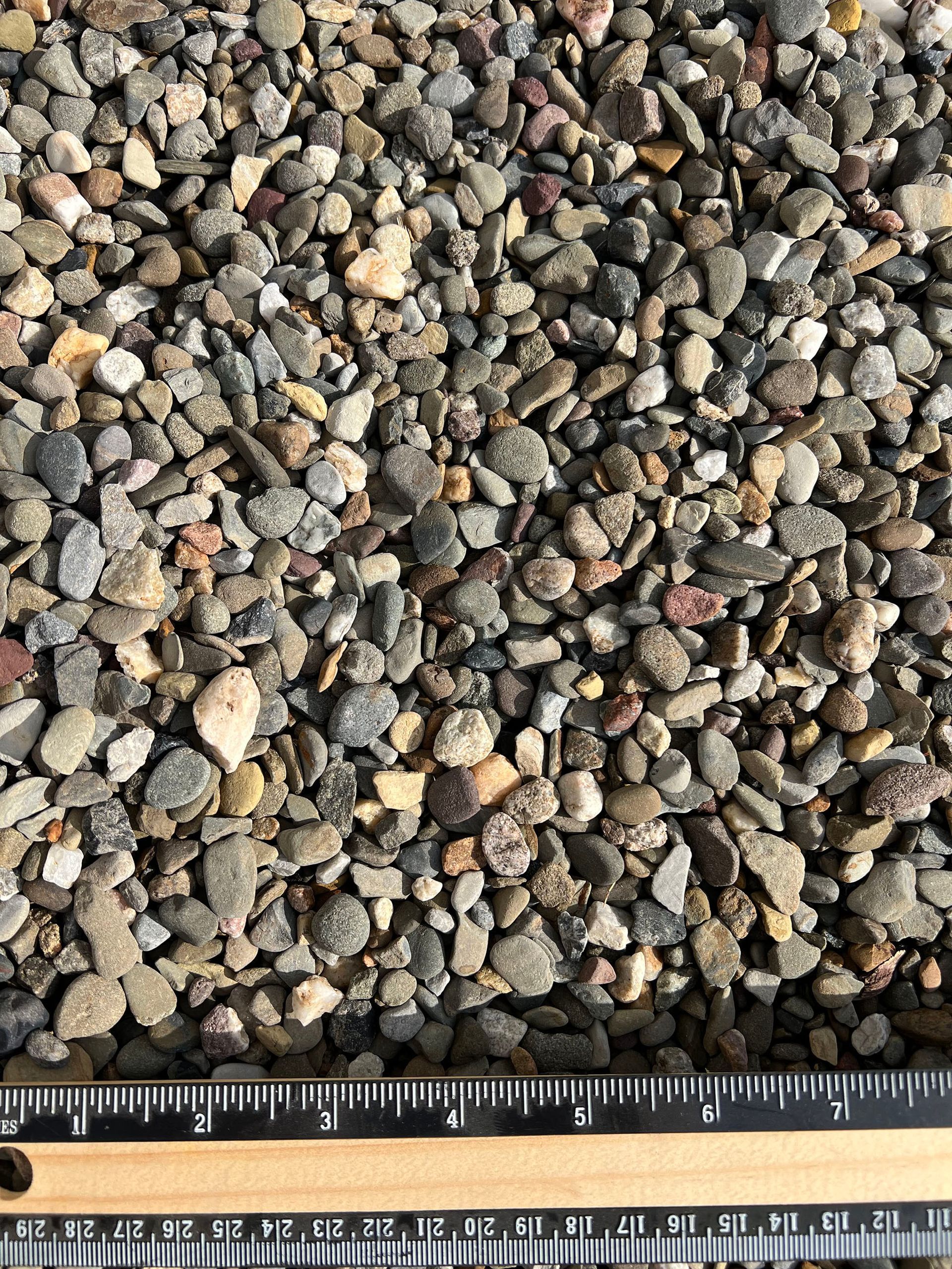 A pile of rocks is being measured by a ruler.