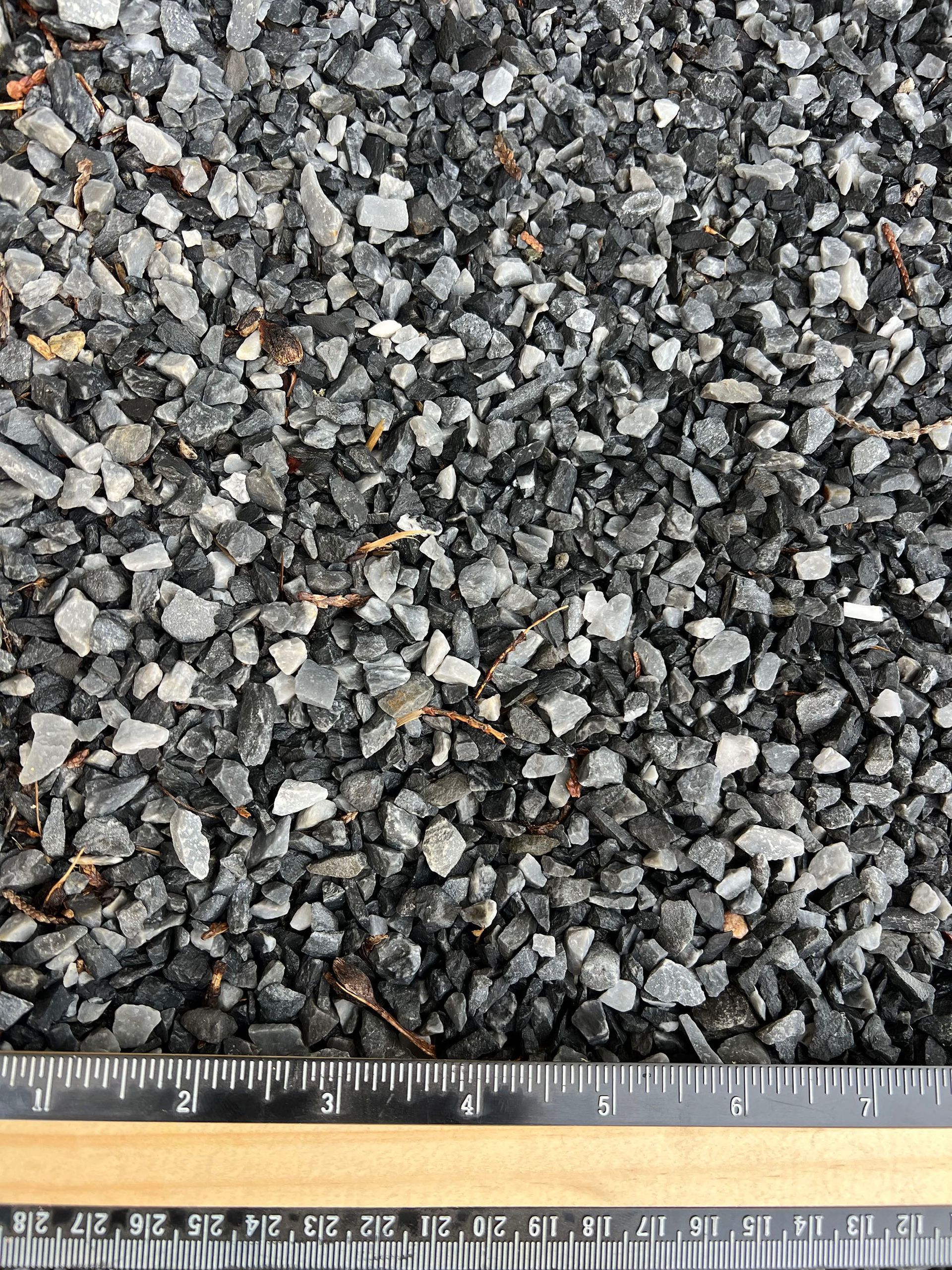 A ruler is laying on top of a pile of gravel.