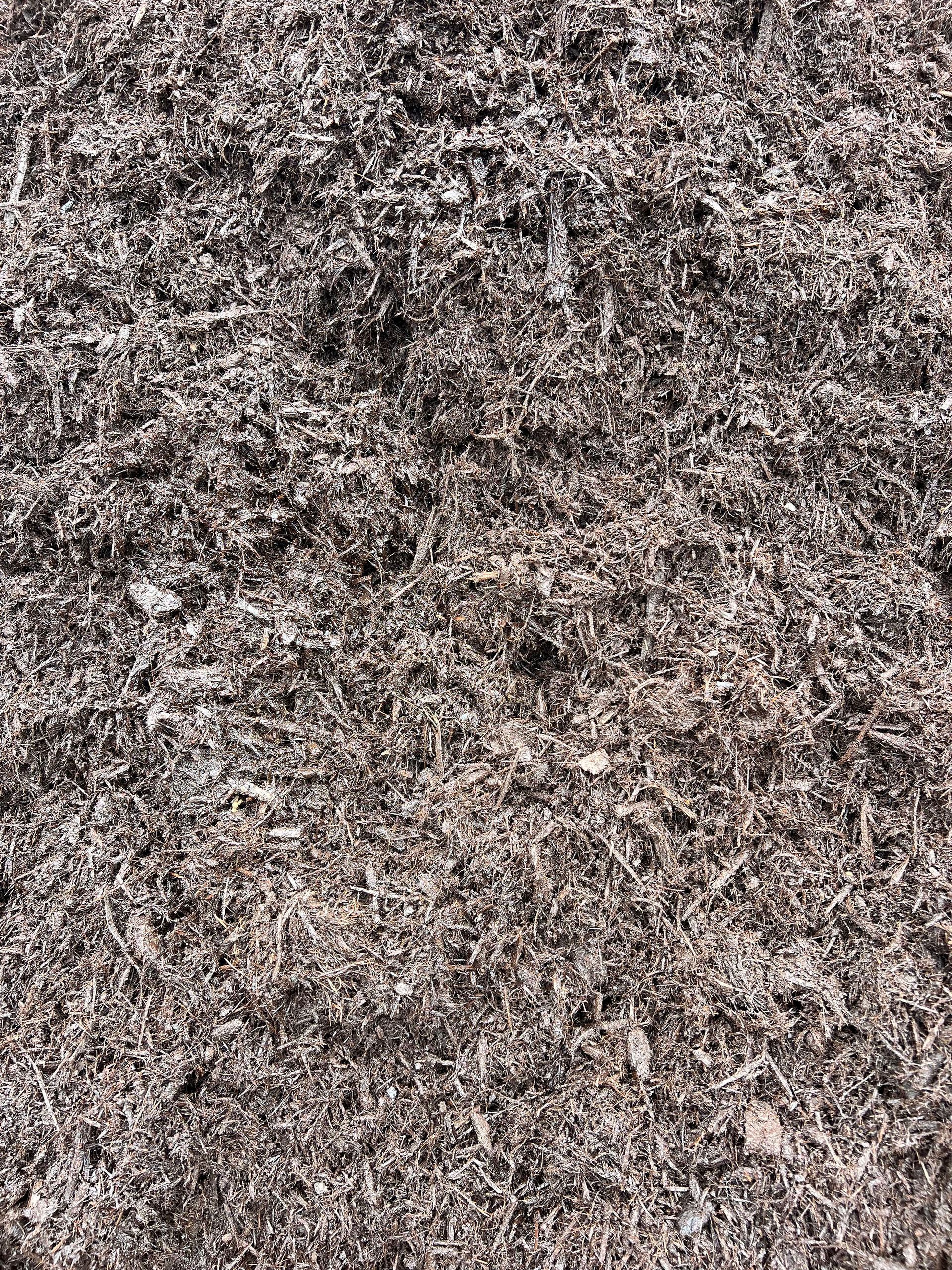 A pile of brown mulch is sitting on the ground.