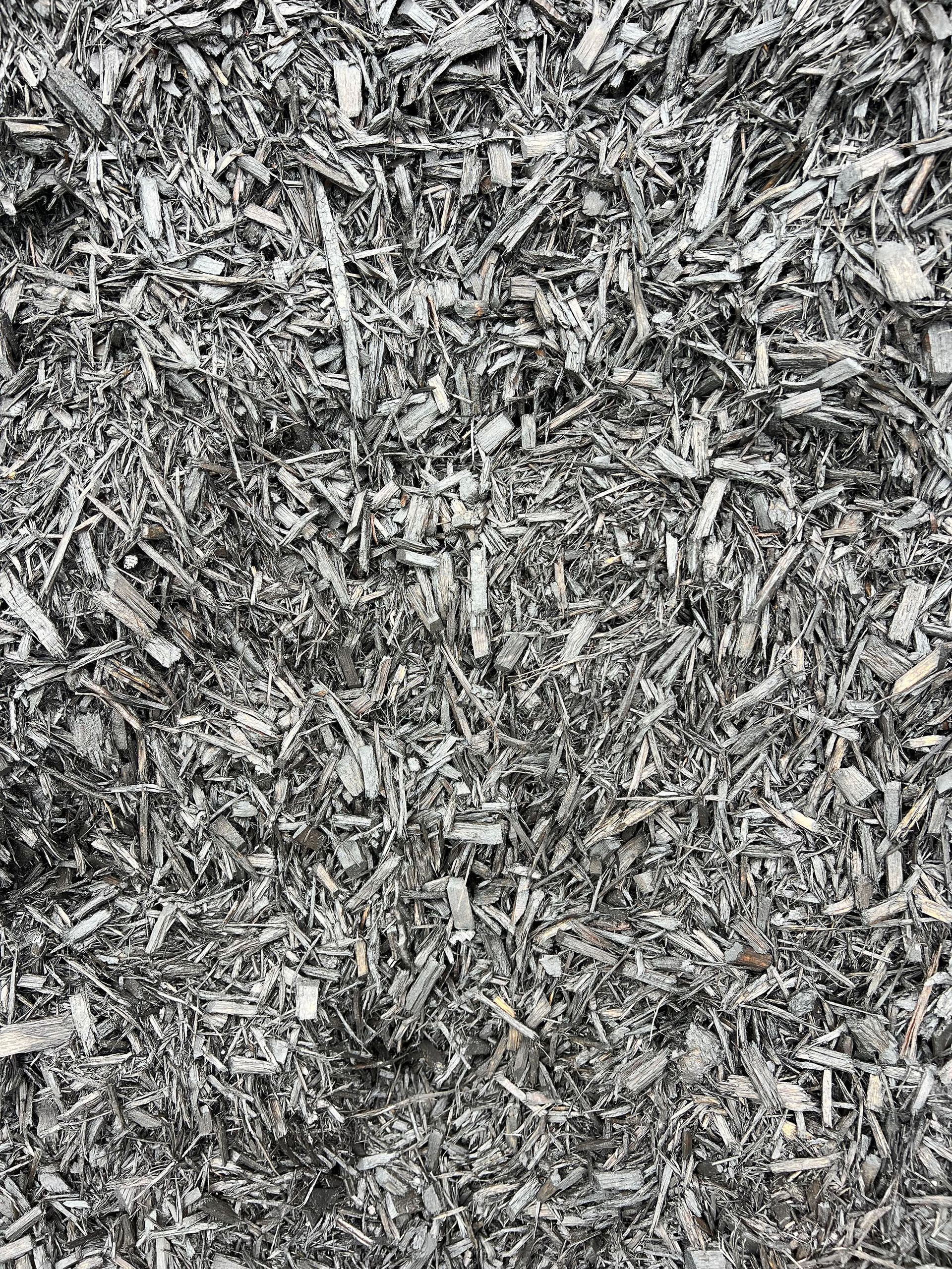 A pile of gray mulch is sitting on the ground.