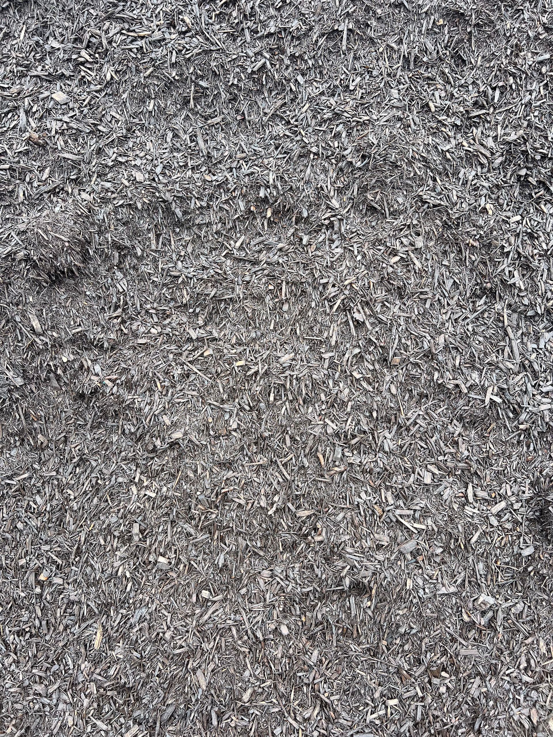A pile of gray mulch is sitting on the ground.