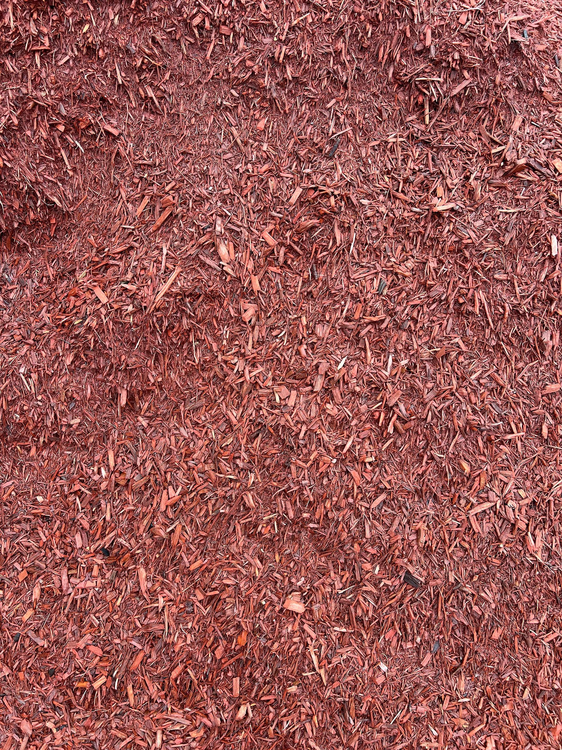 A pile of red mulch is sitting on the ground.