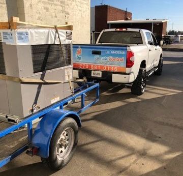 A truck is pulling a trailer with a cooler on it.