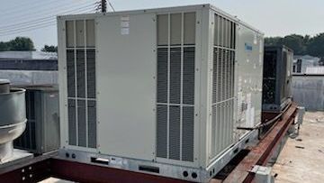 A bunch of air conditioners are sitting on top of a building.