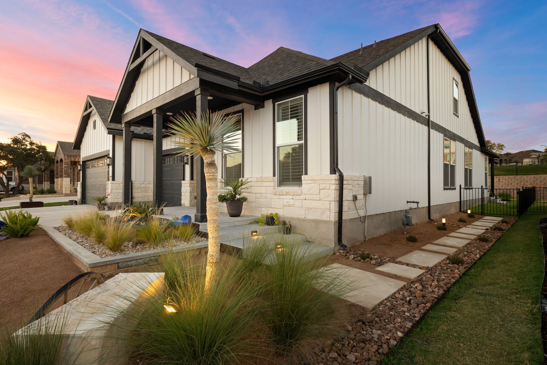 A white house with a black trim and a palm tree in front of it.