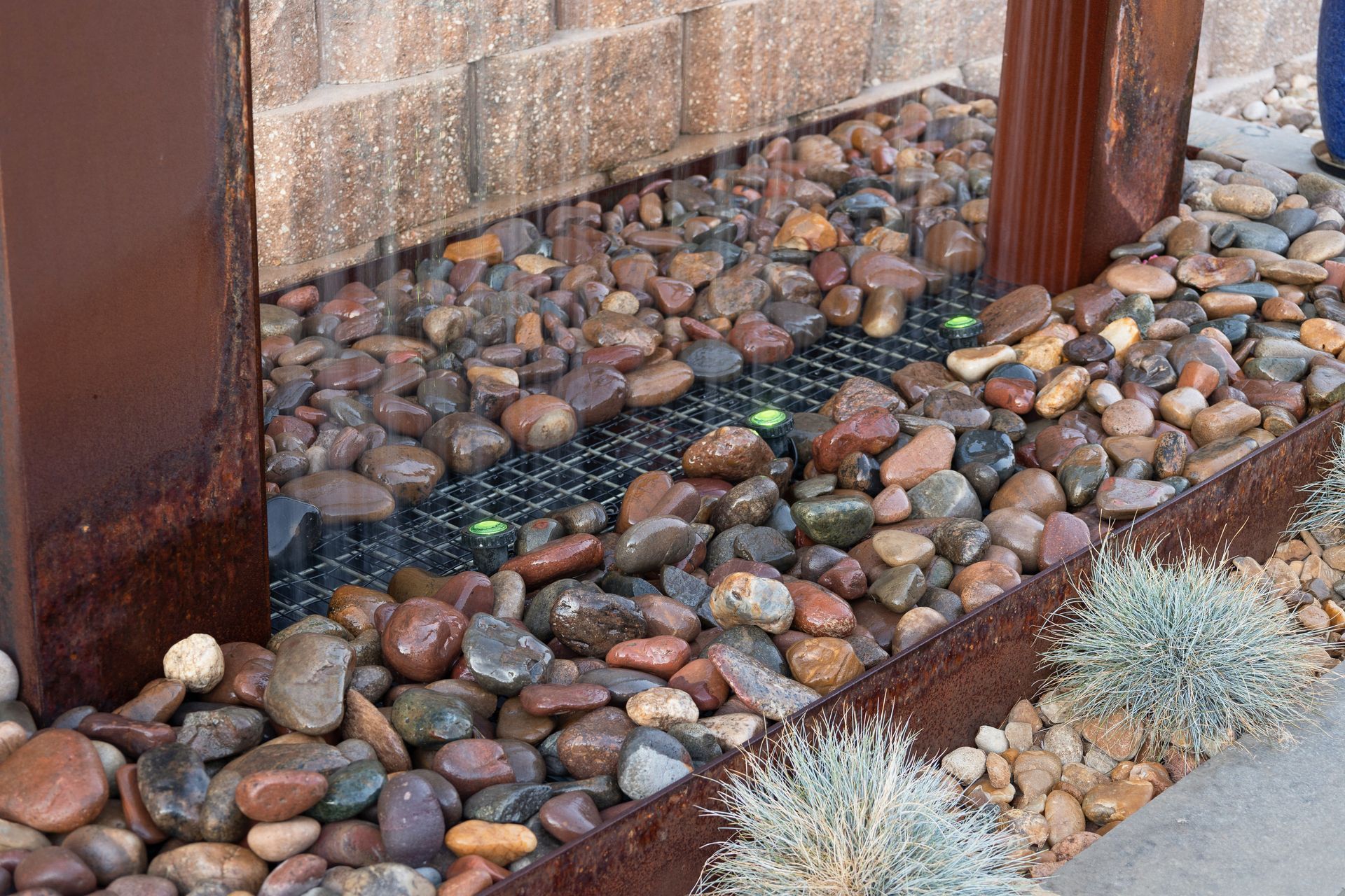 A waterfall is surrounded by rocks and a brick wall.