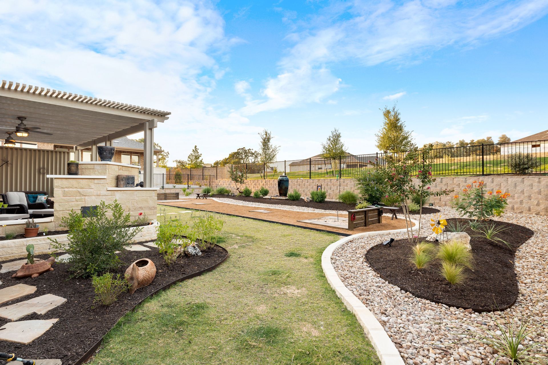A large backyard with a covered patio and a lush green lawn.