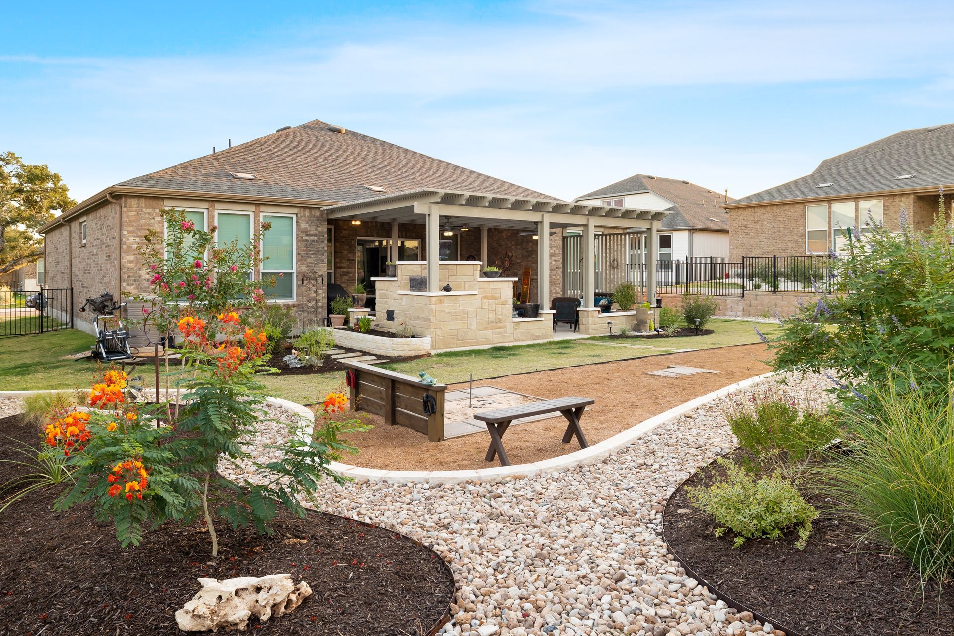 There is a bench in the middle of the yard in front of the house.