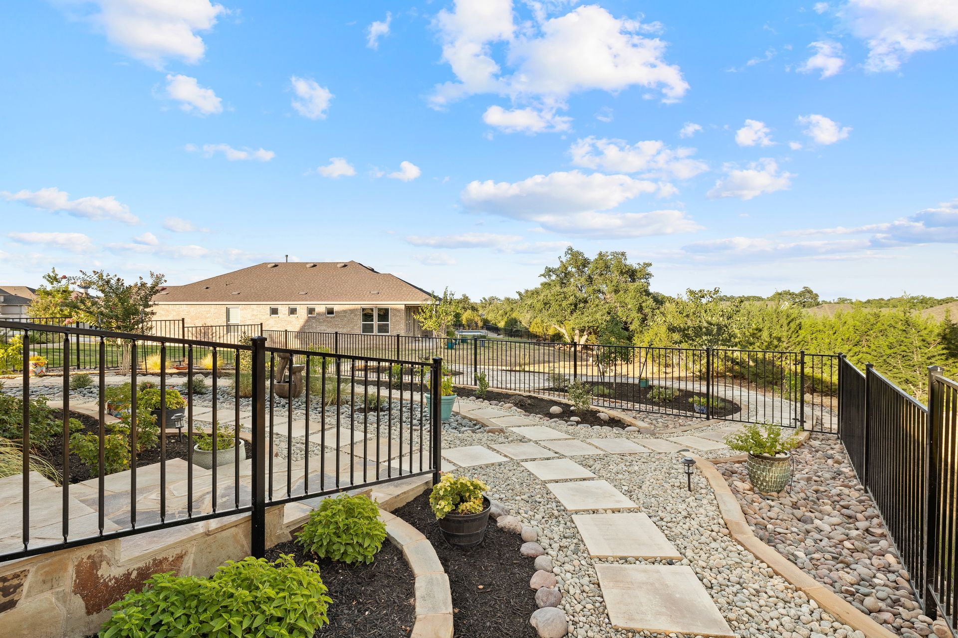 A backyard with a fence and a walkway leading to a house.