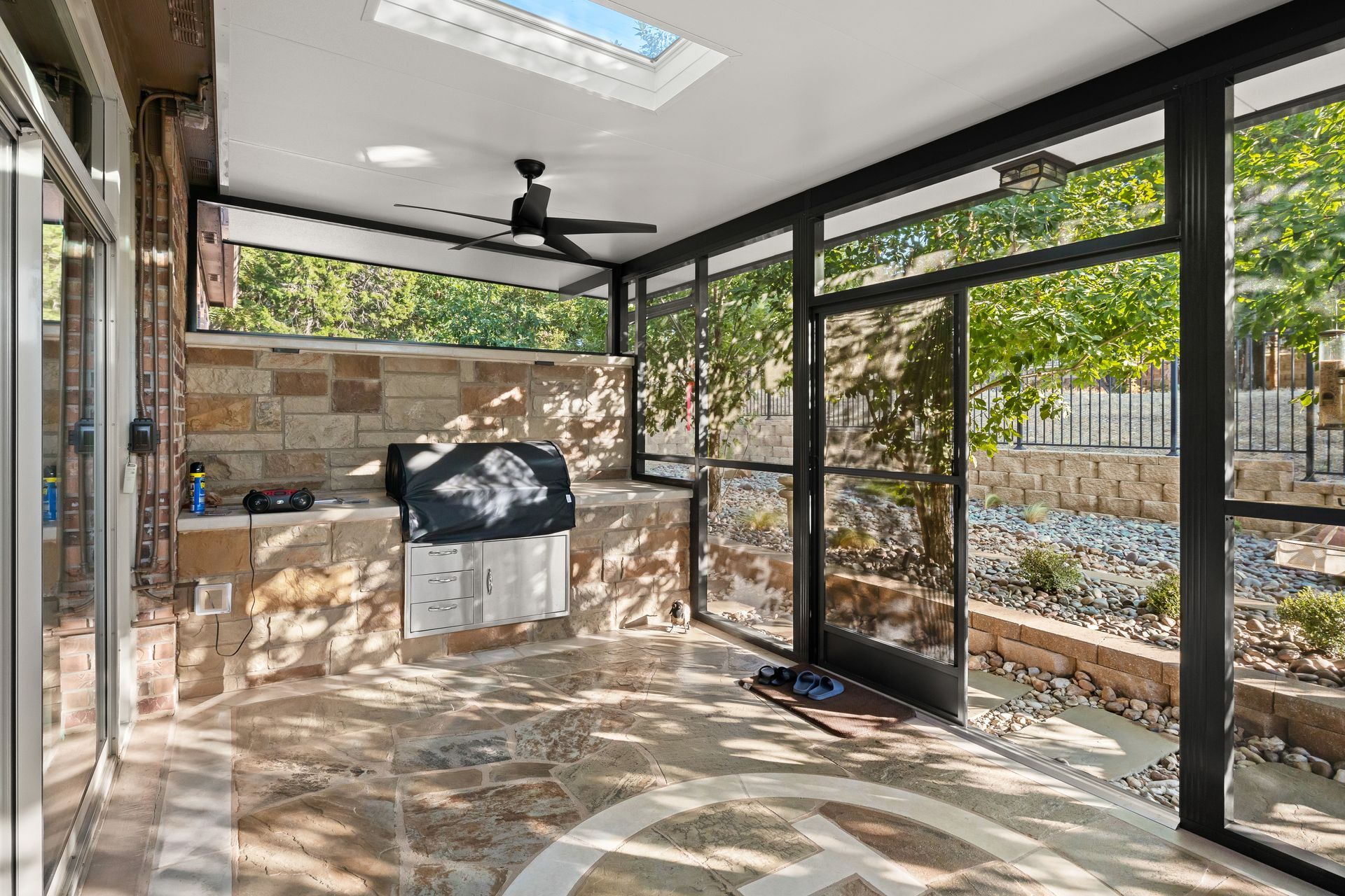 A screened in porch with a ceiling fan and a grill.