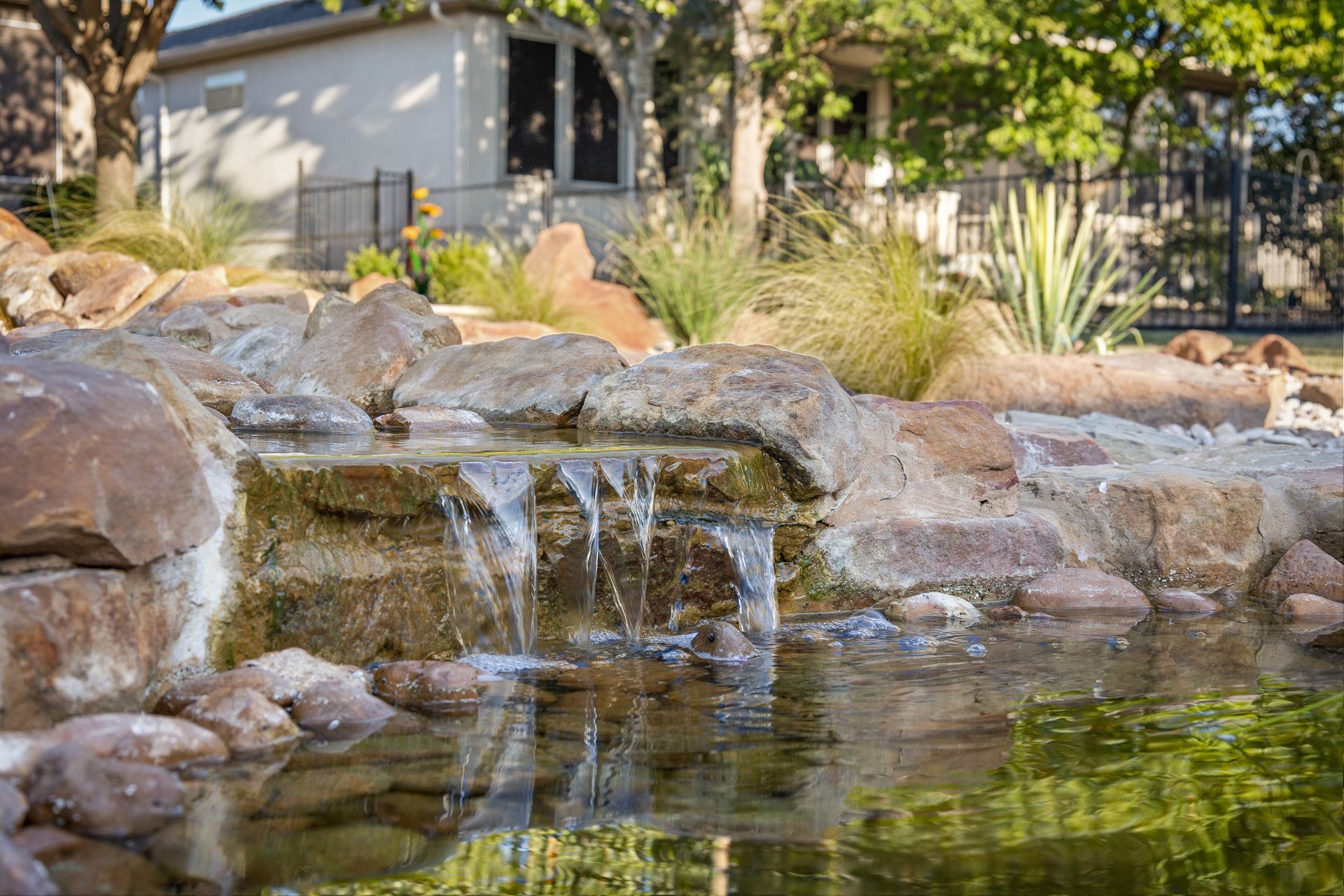 There is a waterfall in the middle of a pond surrounded by rocks.