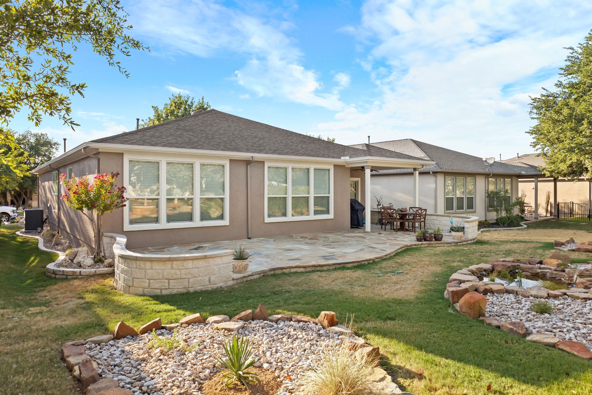 A house with a lot of windows and a patio in the backyard.