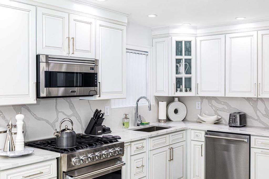 White kitchen with stainless steel appliances and marble countertops.