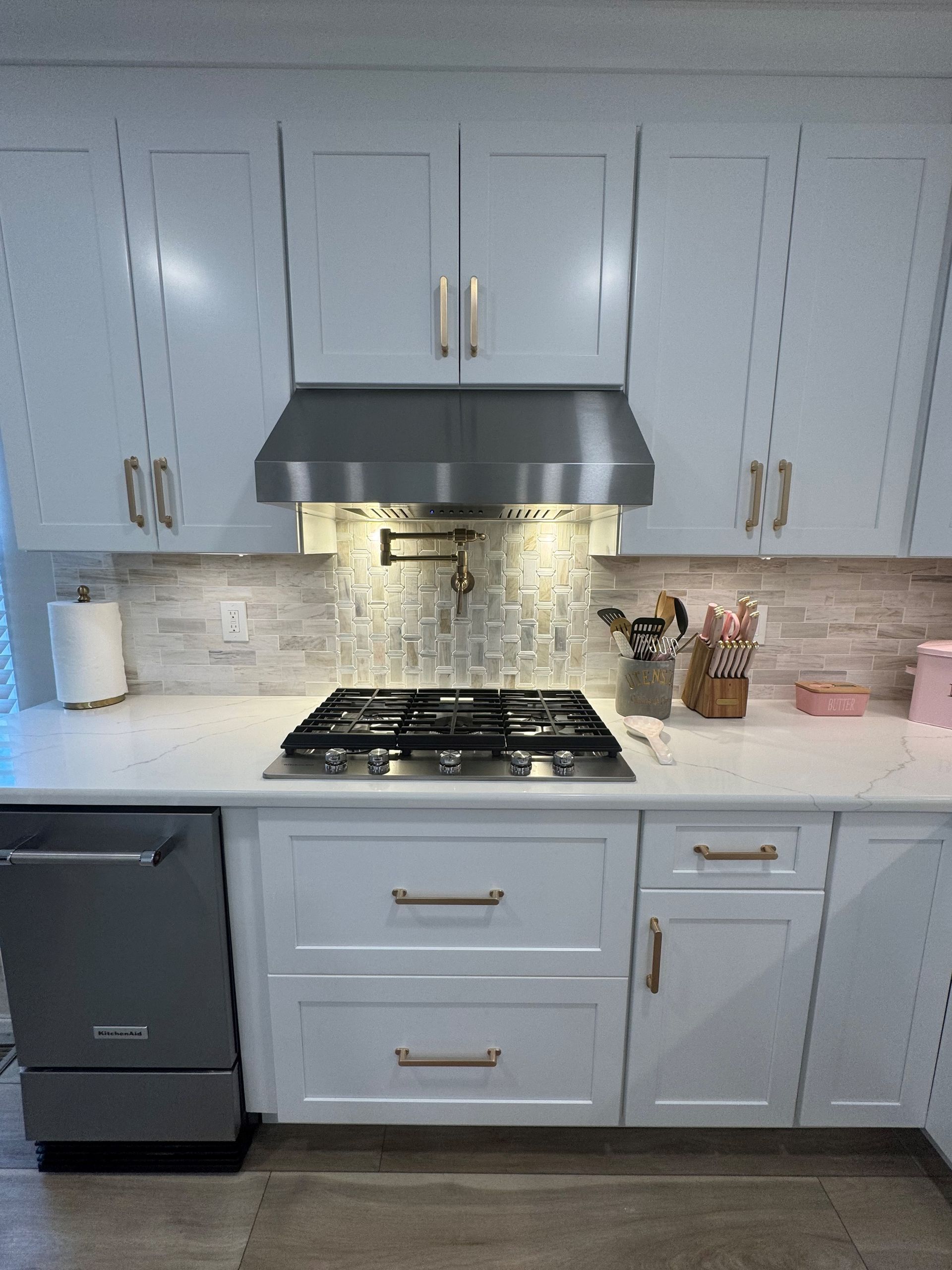 White kitchen with stainless steel appliances and brushed gold hardware.
