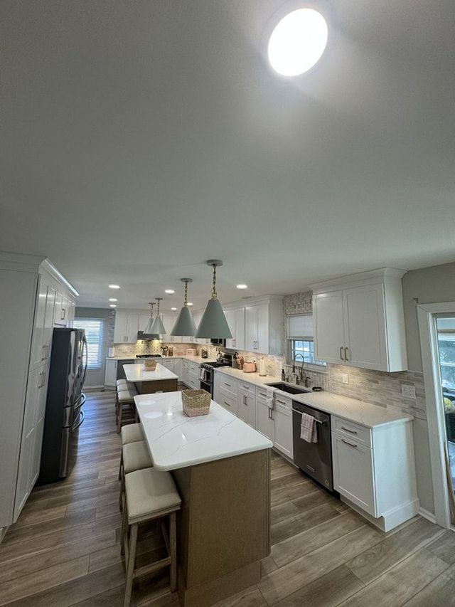 Bright, modern kitchen with multiple islands, white cabinets, and pendant lights.