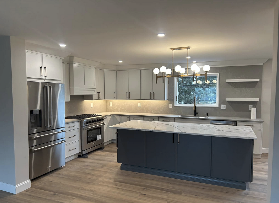 Modern kitchen with gray and white cabinets, stainless steel appliances, and a gray island with a white countertop.
