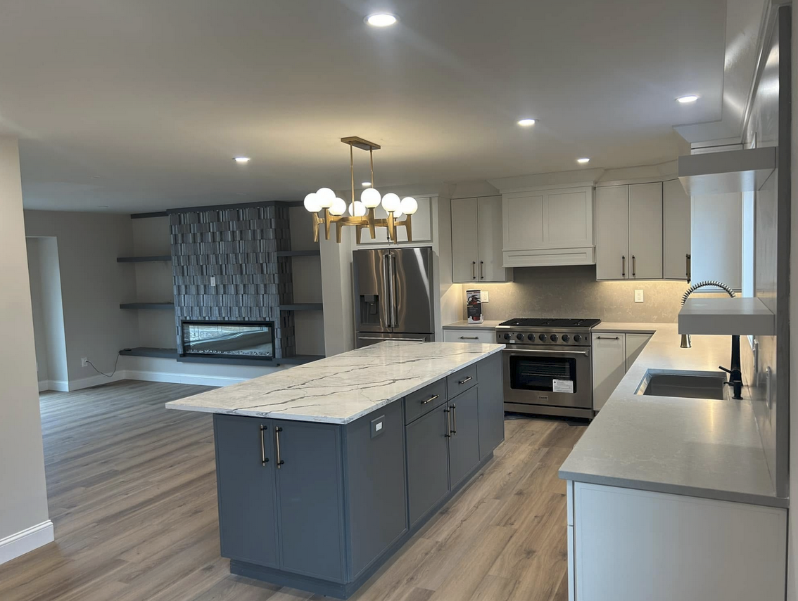 Modern kitchen with grey cabinets, island, and stainless steel appliances.