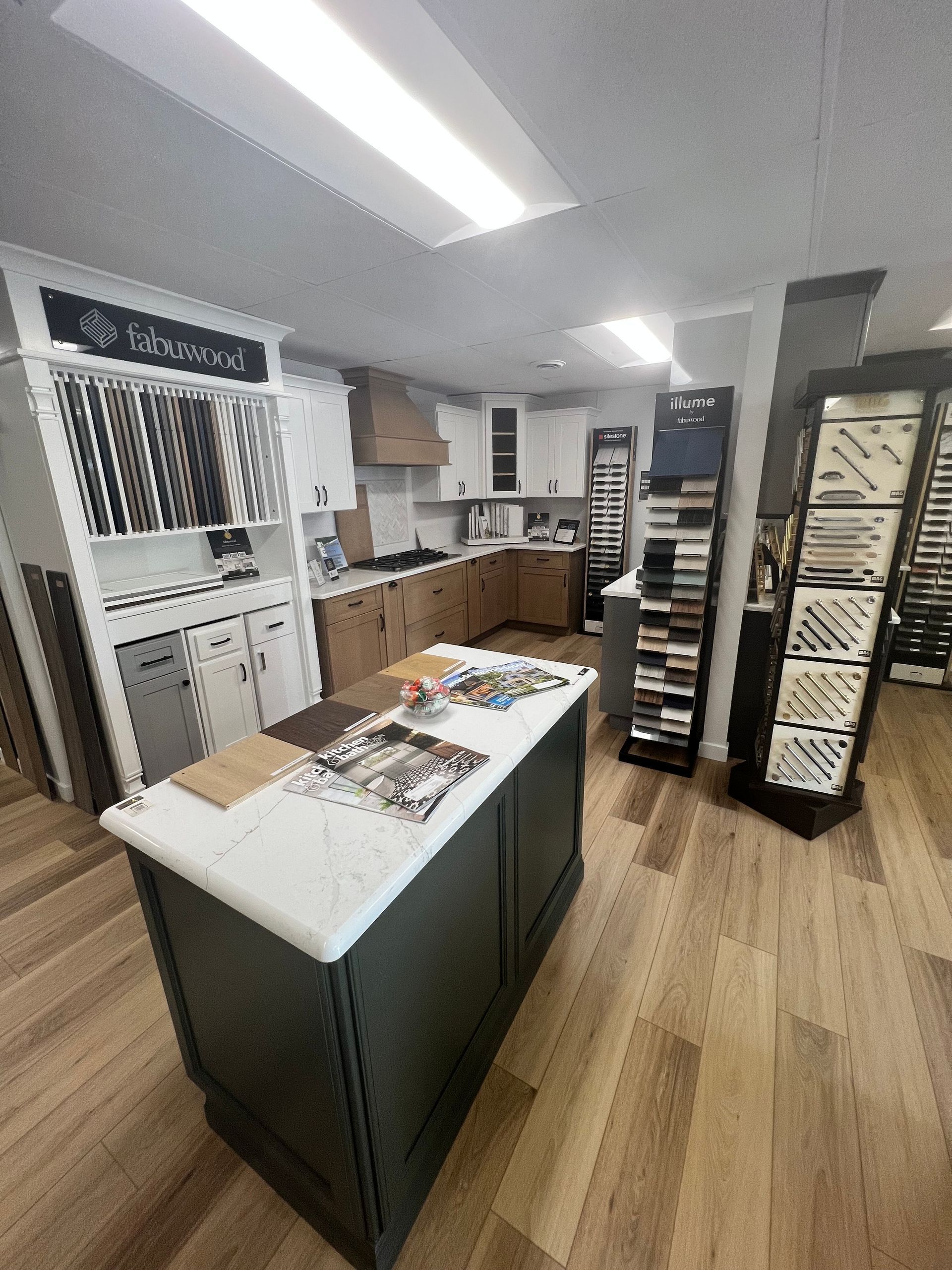 Kitchen showroom with island and cabinets, wood and white, display of samples.