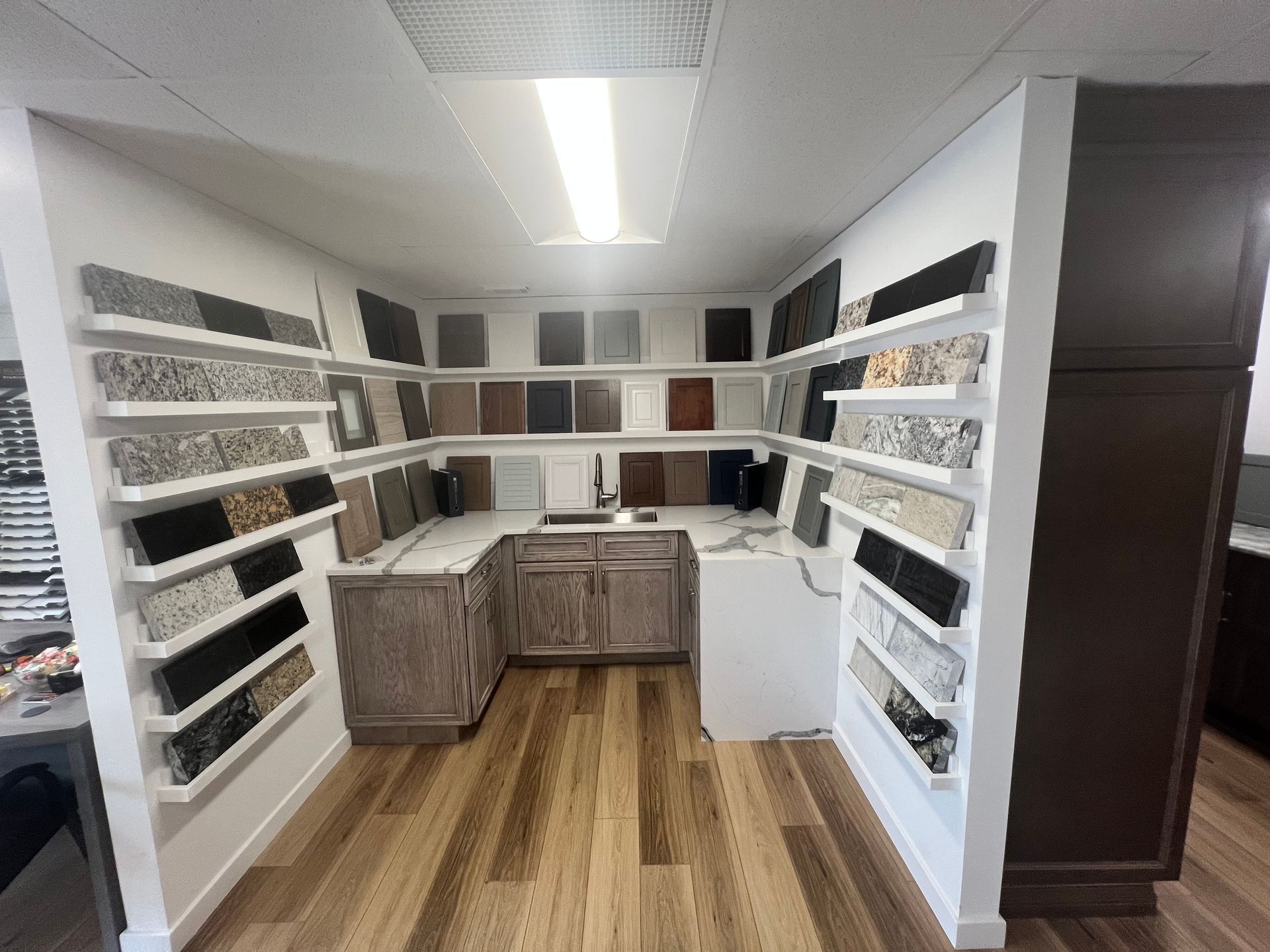 Interior display of stone and cabinet samples in a showroom with wooden floors and bright lighting.