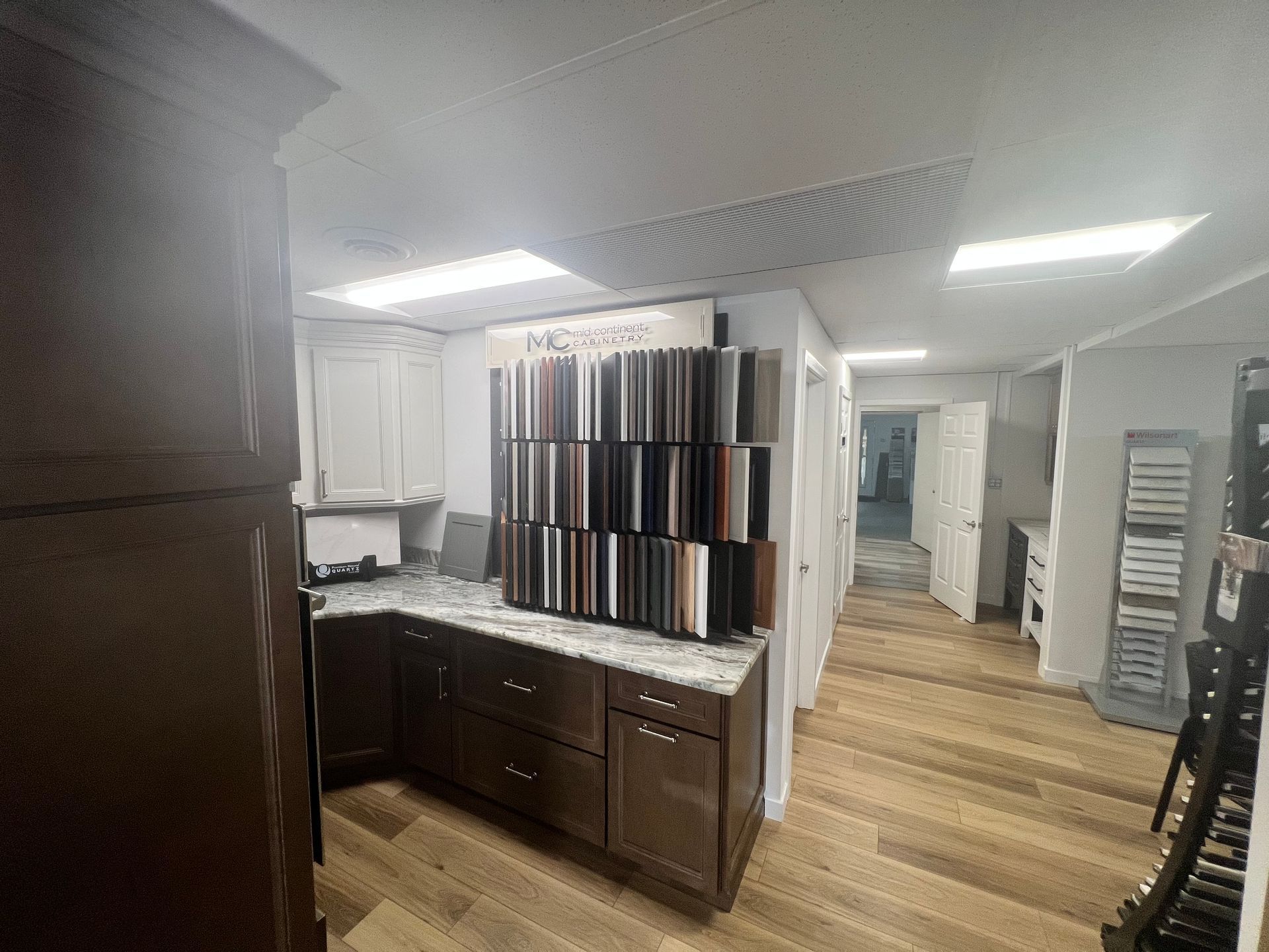 Kitchen showroom with cabinets and countertop samples. Wooden floors, a well-lit space.