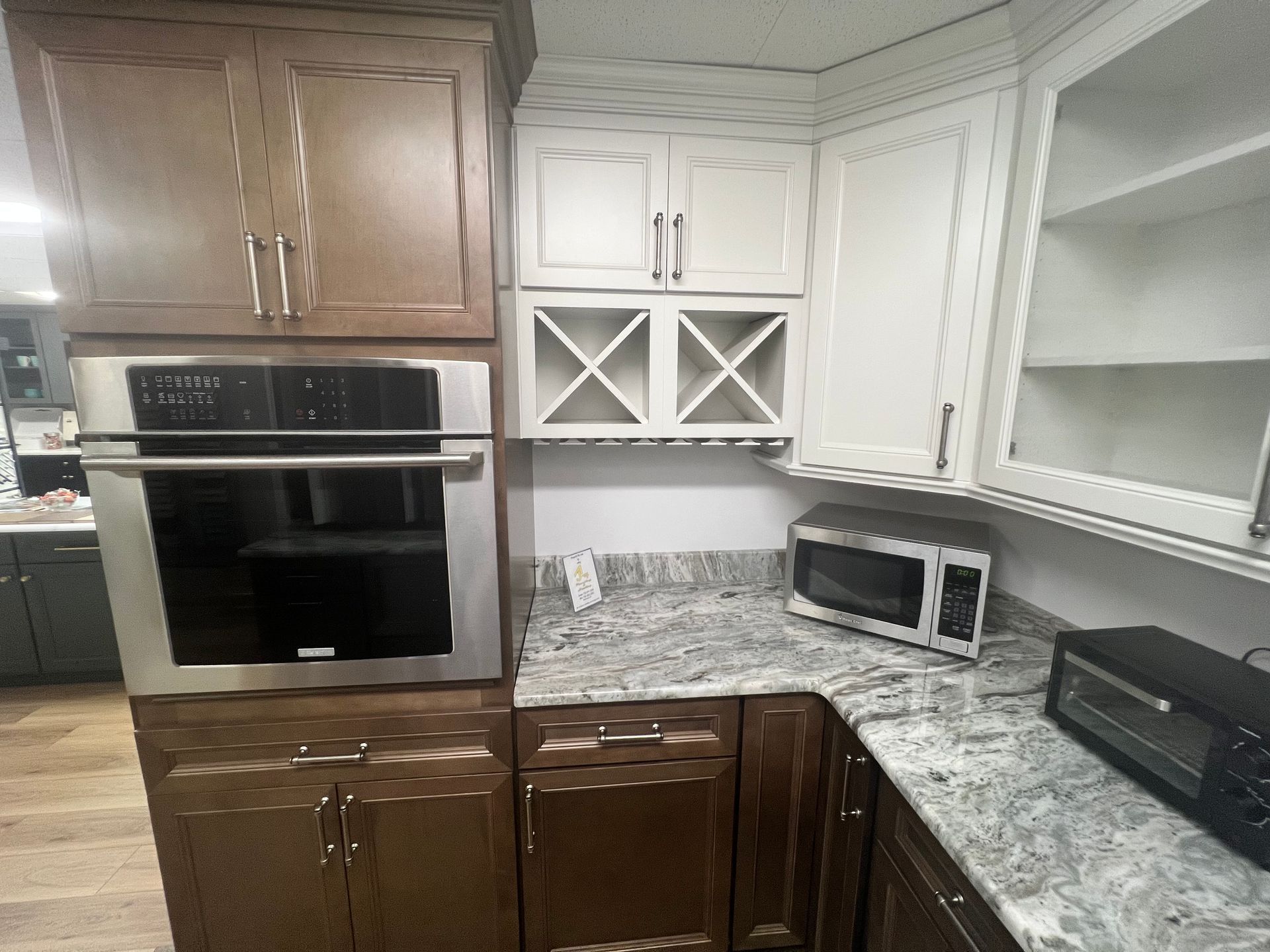 Kitchen with brown and white cabinets, built-in oven, wine rack, microwave, and granite countertop.