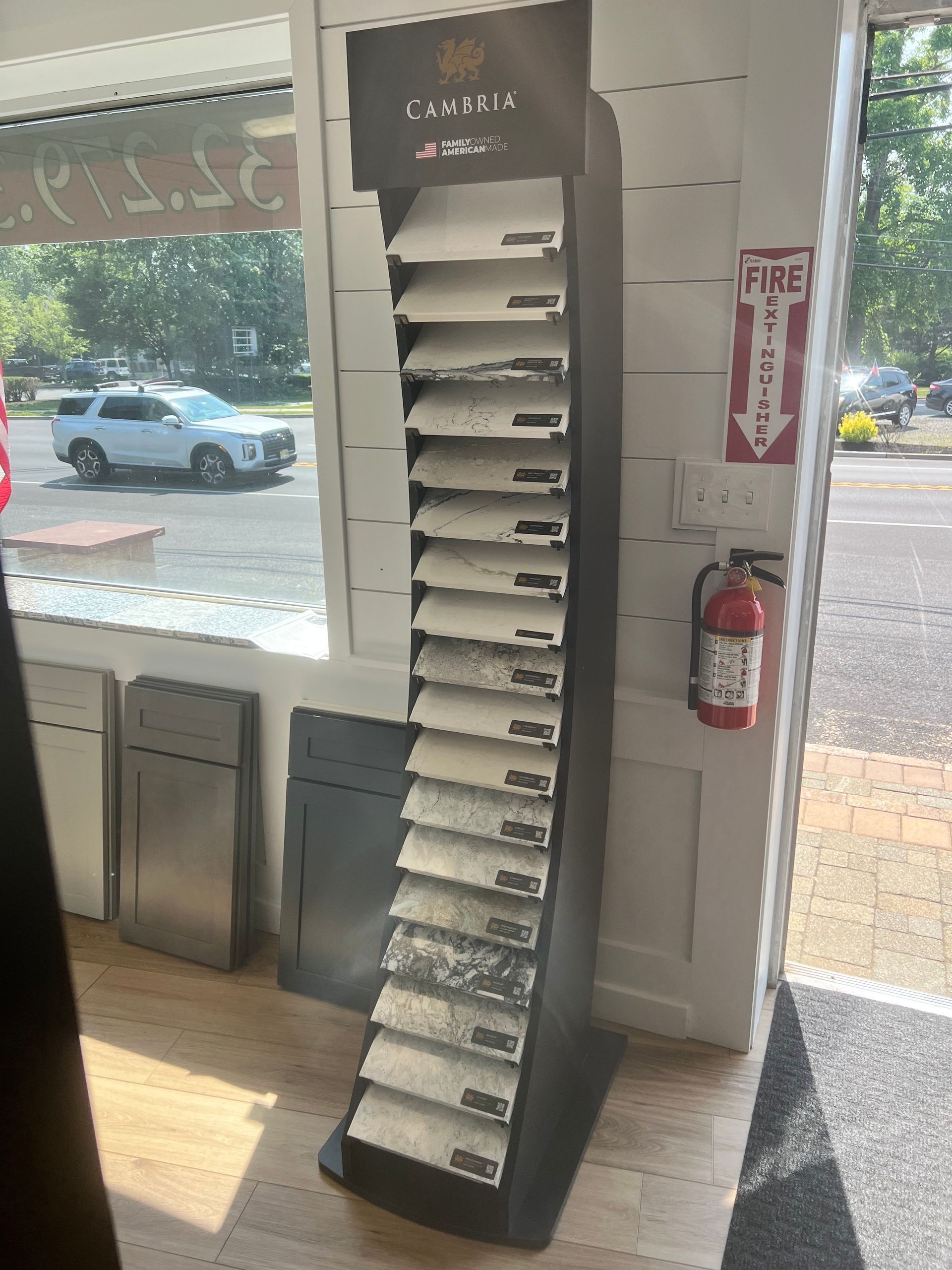 A display stand showing various flooring samples inside a retail space next to a window.
