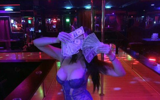 A woman is holding a bunch of money in front of her face