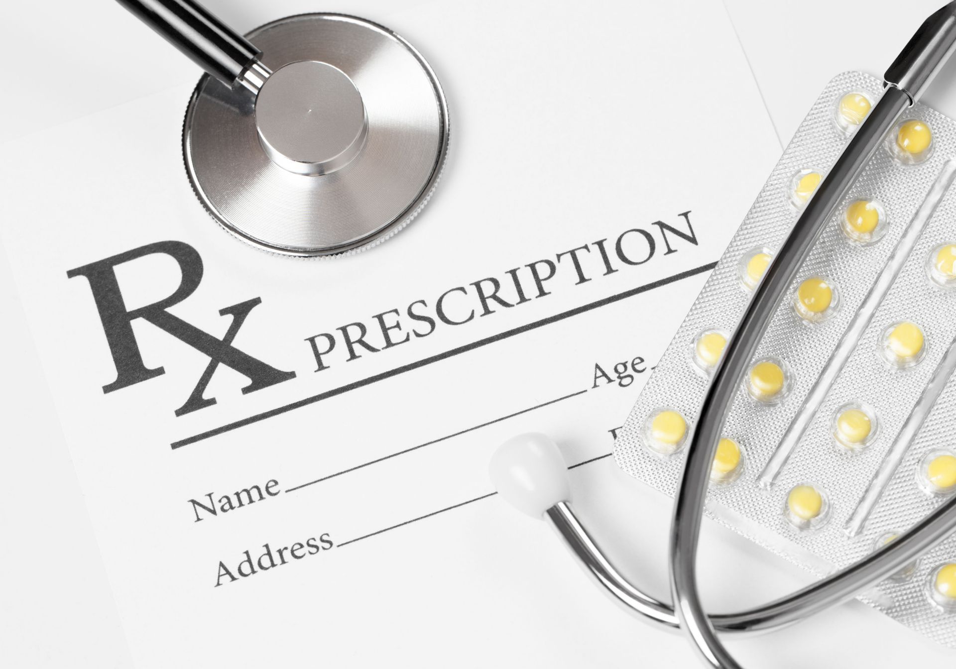 Prescription form with stethoscope and blister pack of pills.